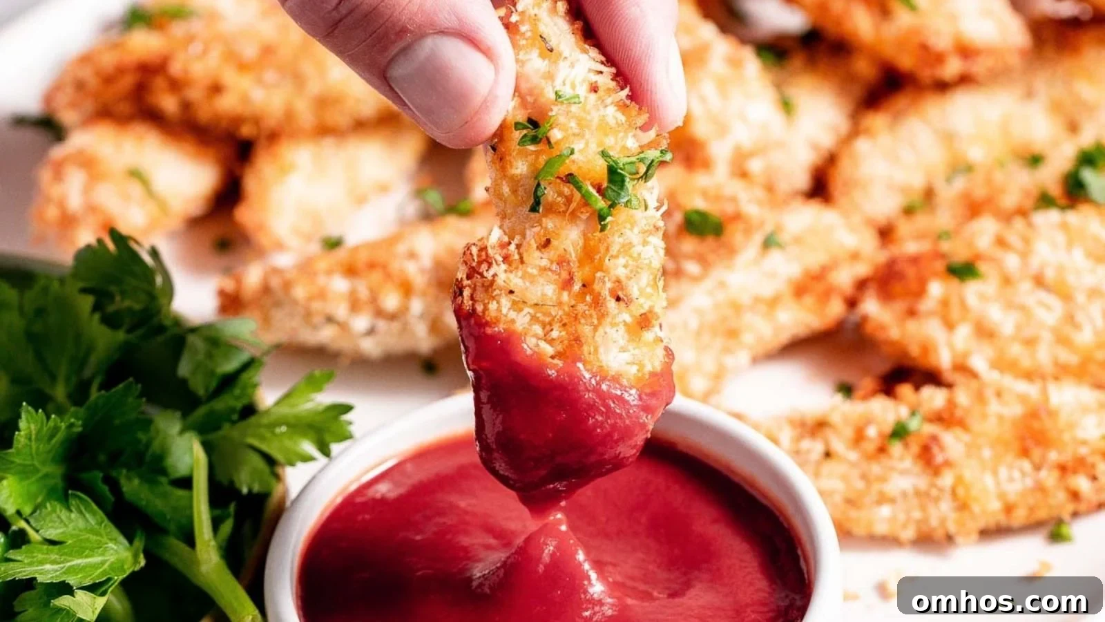 Air fryer chicken tenders crunchy and golden arranged beside dipping sauce.