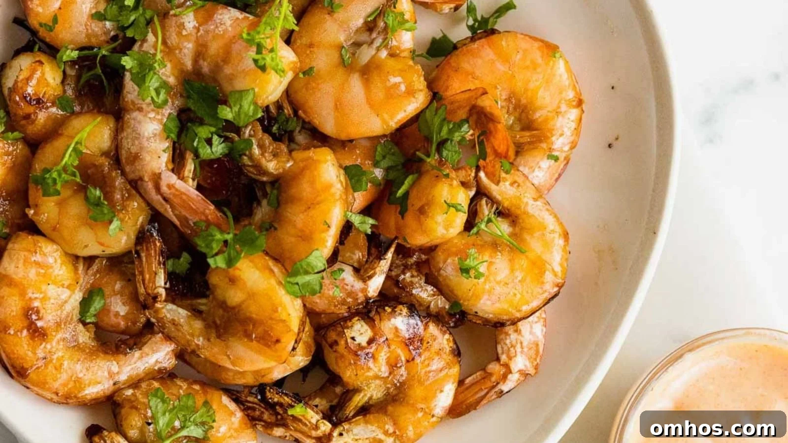 Air fryer shrimp lightly crisped with golden edges arranged on a white plate.