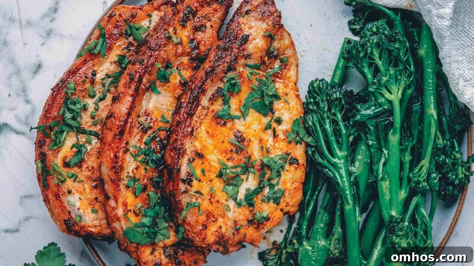 Air fryer pork chops browned with juicy centers served beside fresh herbs.
