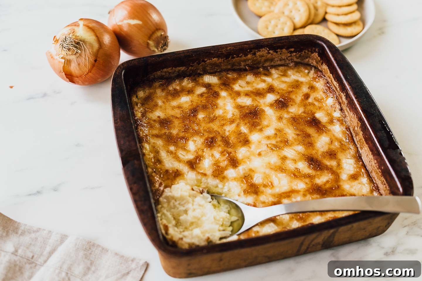 Hot onion dip with a spoon in the dish.
