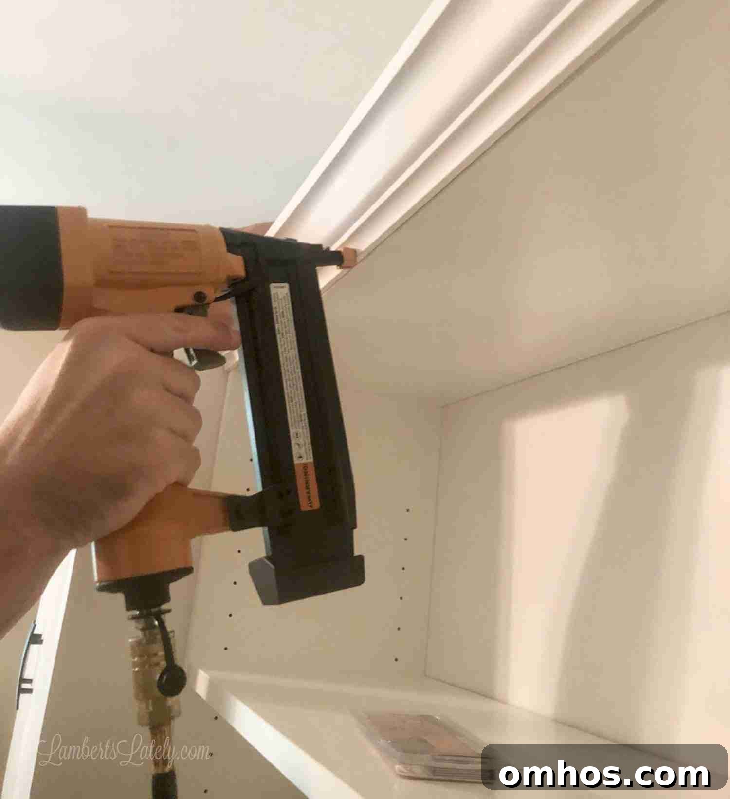 DIY Murphy Bed with Built-In Desk and IKEA Bookcases 12 using a pneumatic nail gun to install crown molding on a shelf.