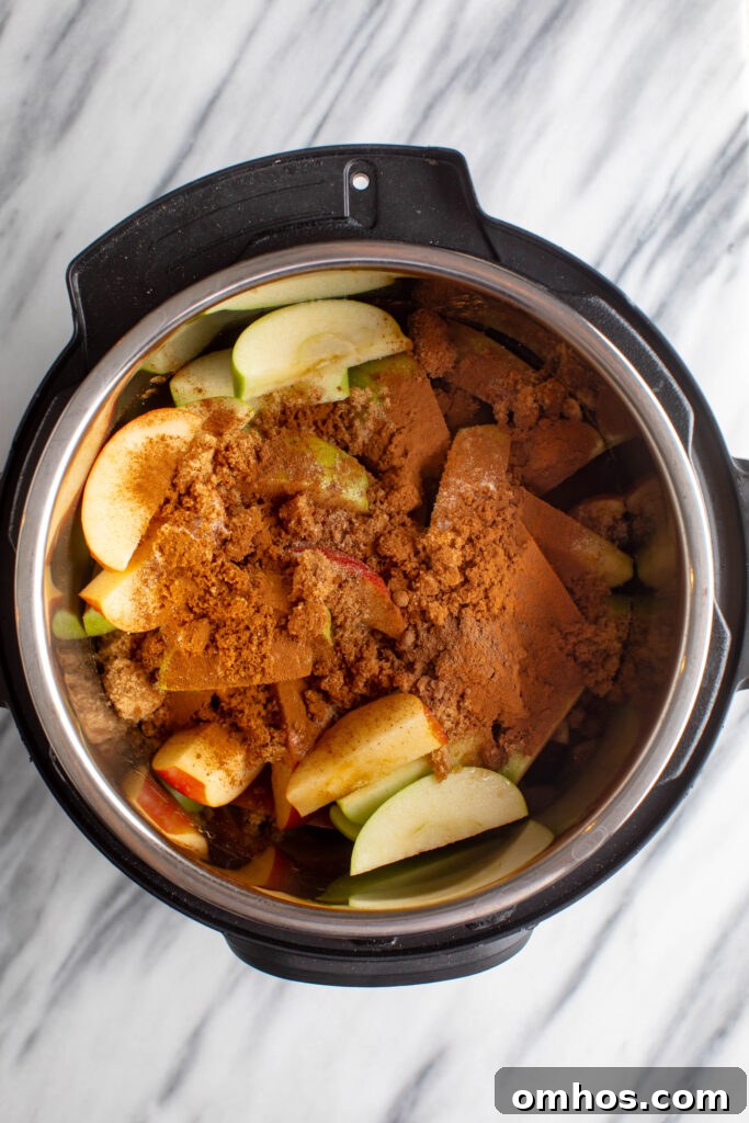 No-Peel Instant Pot Apple Butter Recipe 5 instapot with sliced red and green apples topped with water, brown sugar, cinnamon and salt