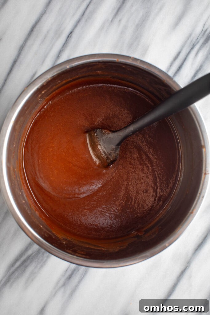 No-Peel Instant Pot Apple Butter Recipe 9 blended apples, maple syrup, vanilla extract and lemon juice mixed thoroughly in a silver bowl with a black spatula