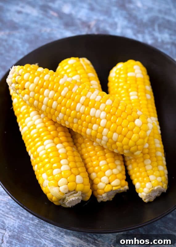 25 Quick Instant Pot Side Dish Recipes for Weeknights 10 4 cobs of corn on a black plate sitting on a wooden table.