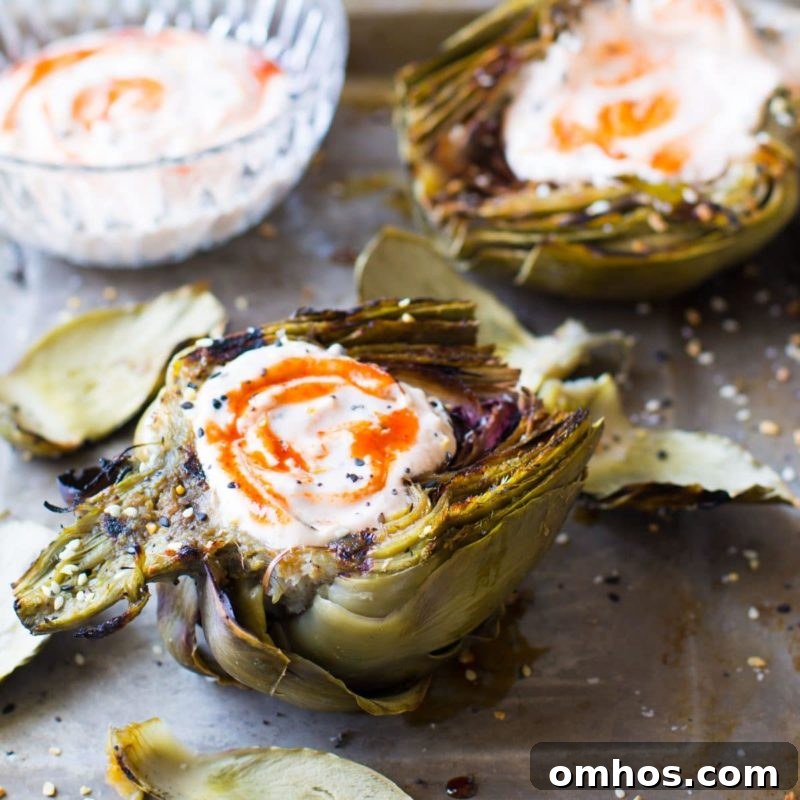 25 Quick Instant Pot Side Dish Recipes for Weeknights 2 Grilled Artichokes topped with a Sriracha Dipping Sauce on a countertop, dipping sauce on side.