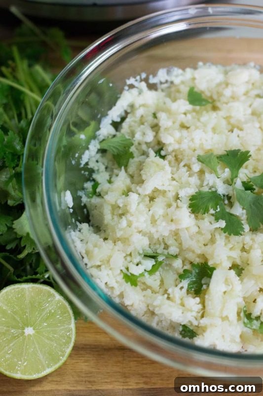 25 Quick Instant Pot Side Dish Recipes for Weeknights 22 Glass bowl containing cauliflower cilantro rice topped with cilantro, lime on wooden table.