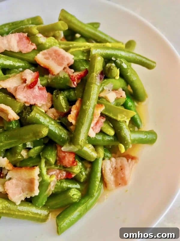 25 Quick Instant Pot Side Dish Recipes for Weeknights 7 Cooked Green beans with bacon in a white plate cooked in an Instant Pot.
