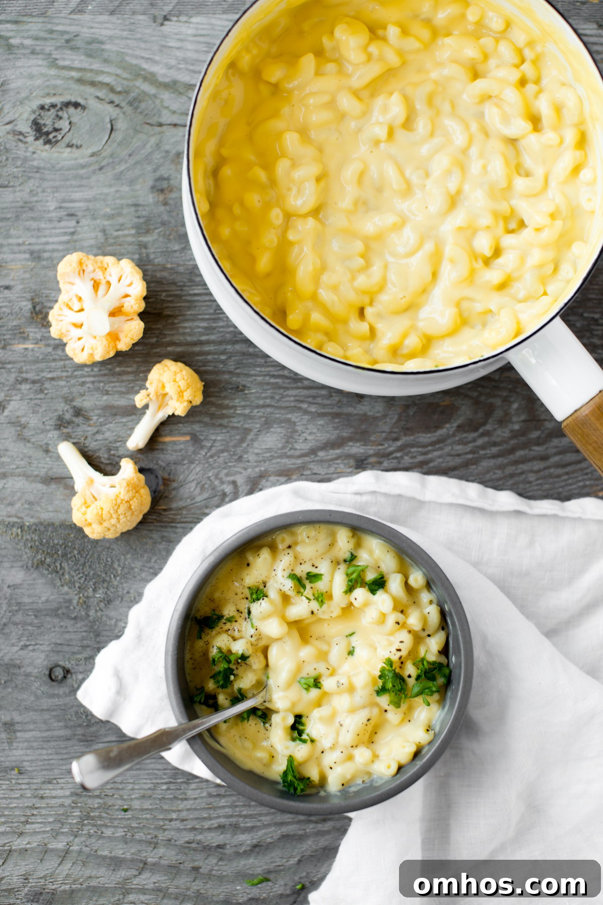 bowl of stovetop cauliflower mac and cheese with parsley and gray background