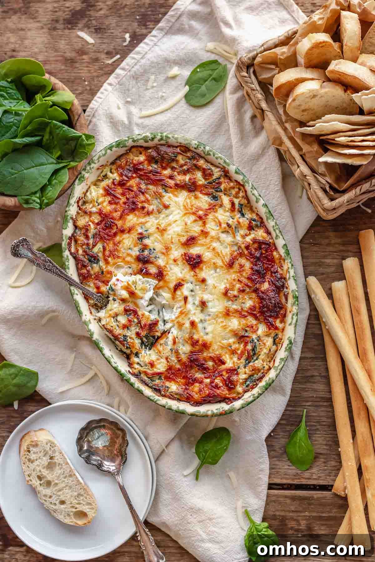 A spoon inserted into crab spinach artichoke dip.