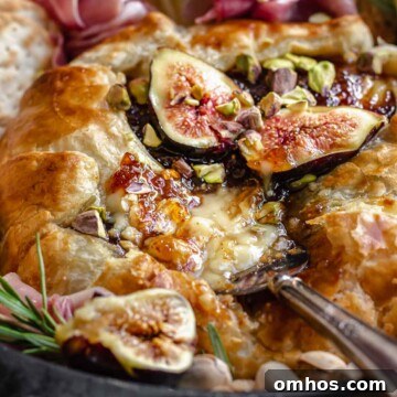 Close up of baked brie with fig jam and a scrip being removed.