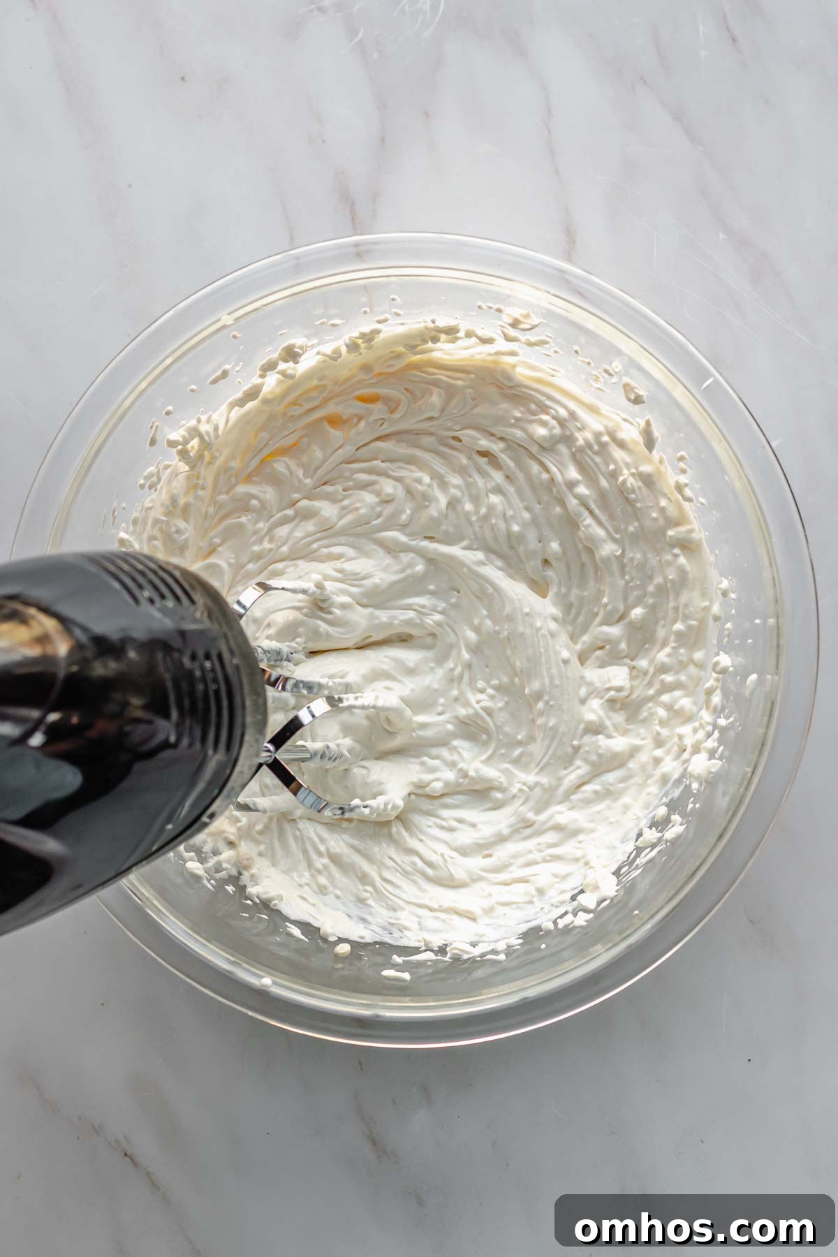 A hand mixer mixes together the wet ingredients in a bowl.