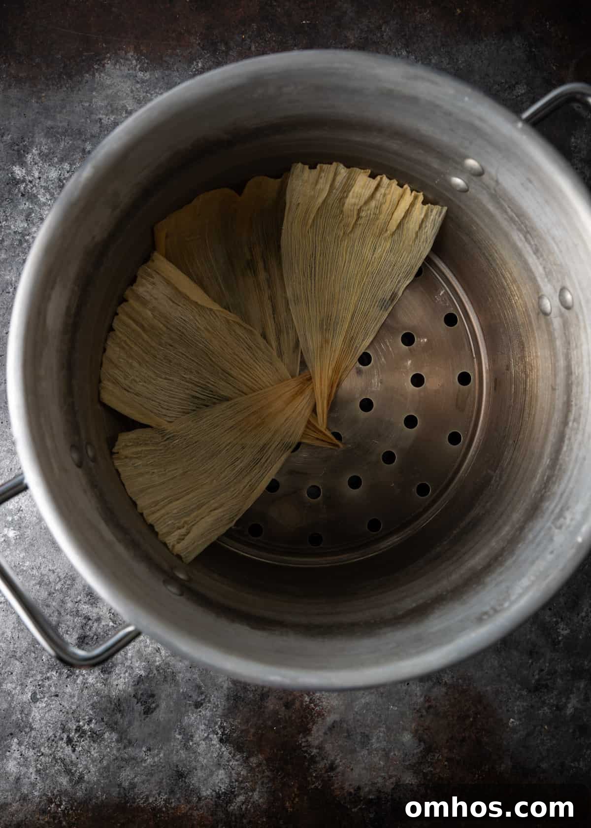 Authentic Mexican Red Pork Tamales Recipe 15 overhead process shot: titled image (and shown) layer bottom with husks
