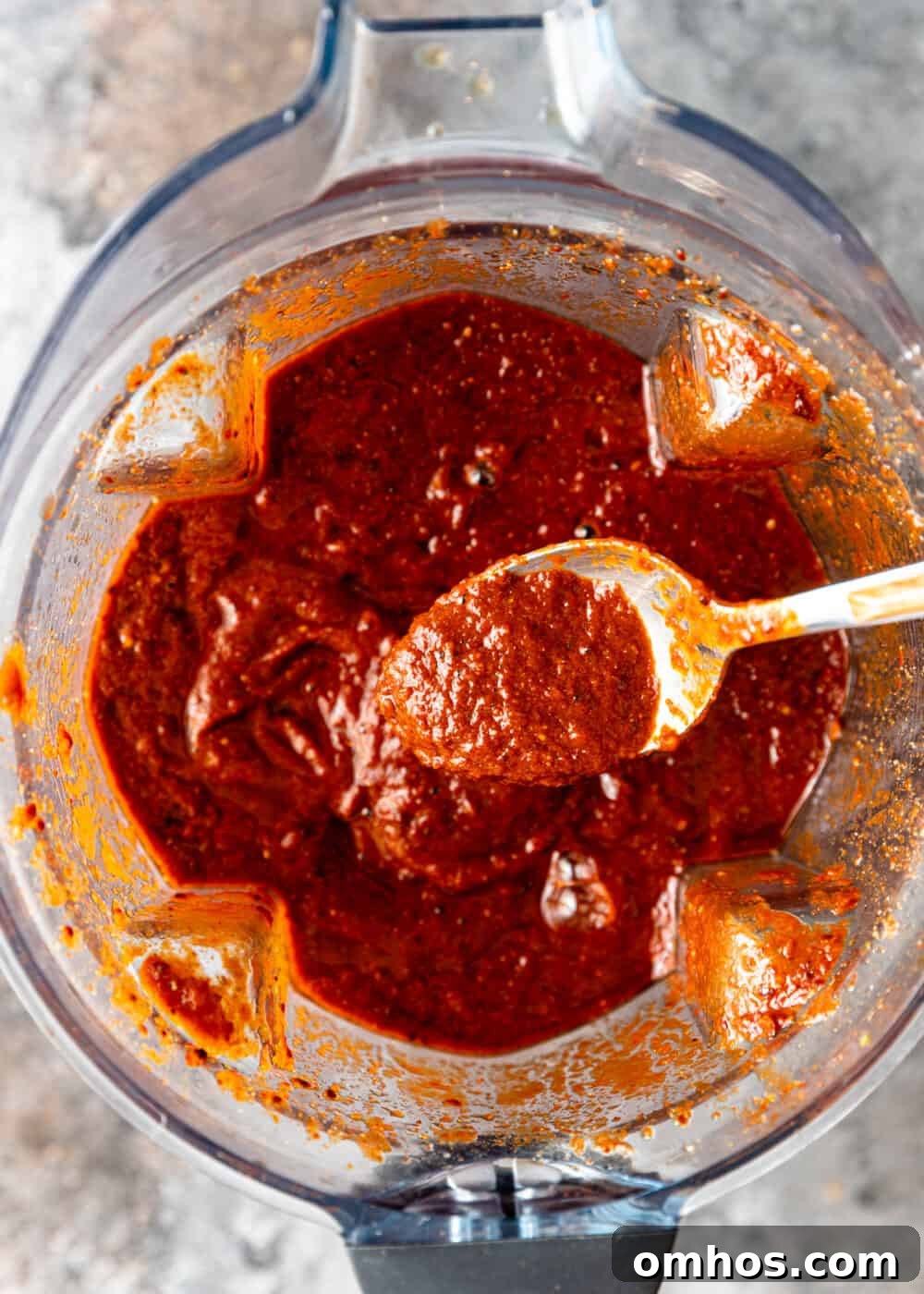 Authentic Mexican Red Pork Tamales Recipe 4 overhead process shot: spoonful of blended pork rojo sauce for tamales over rest of the sauce