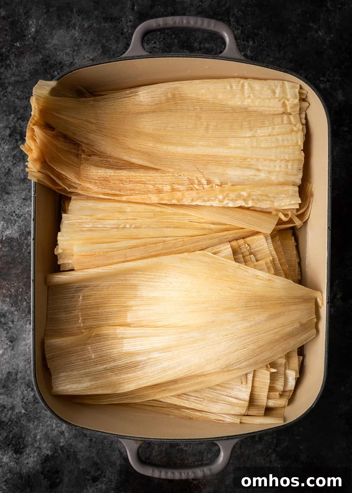 Authentic Mexican Red Pork Tamales Recipe 6 overhead process shot: titled image (and shown) soaked husks