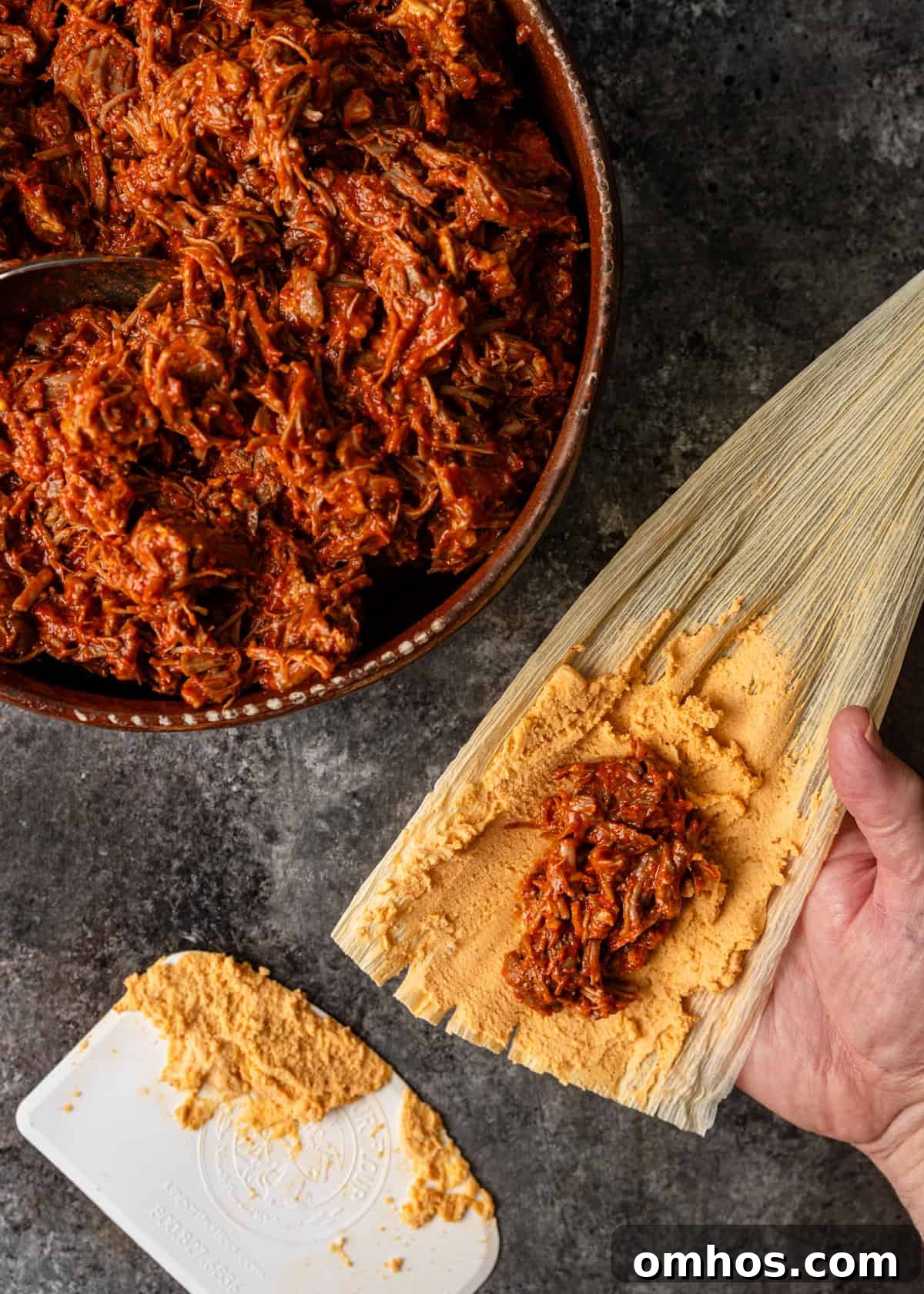 Authentic Mexican Red Pork Tamales Recipe 8 overhead process shot: titled image (and shown) add filling on masa
