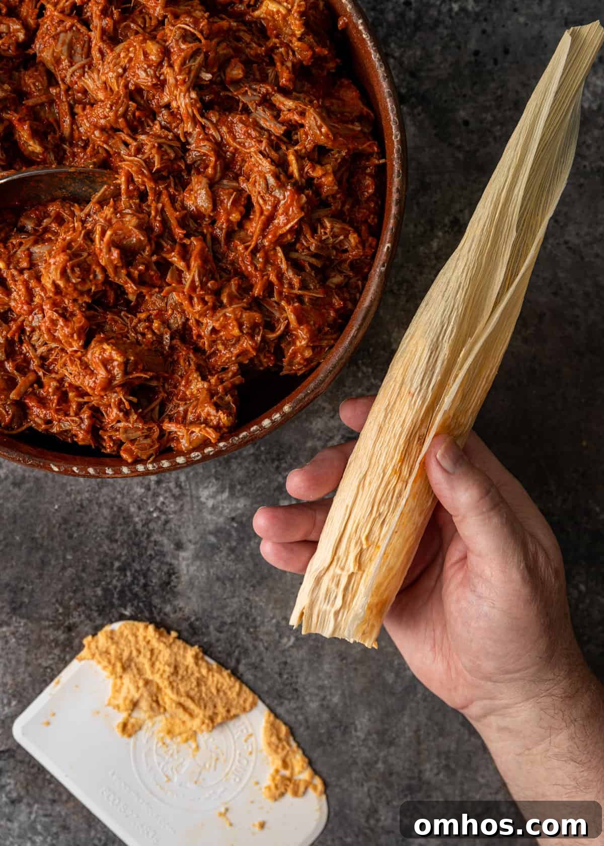 Authentic Mexican Red Pork Tamales Recipe 9 overhead process shot: titled image (and shown) fold over husk