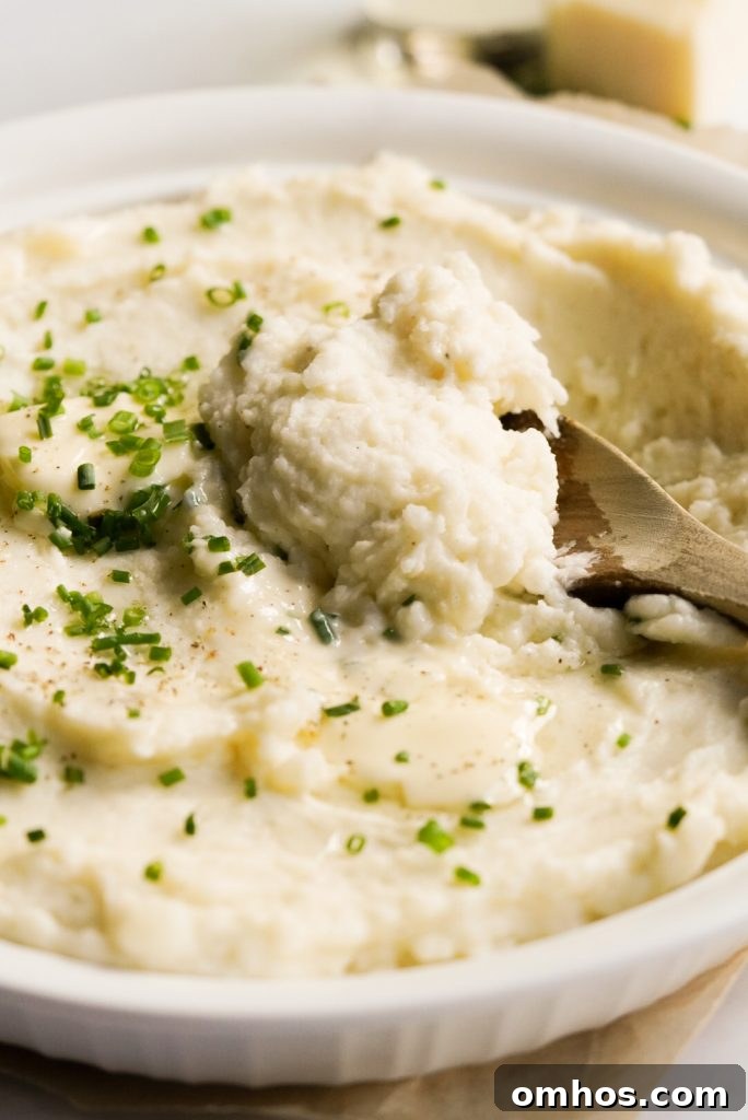 truffle mashed potatoes in a dish with a wooden spoon scooping some out