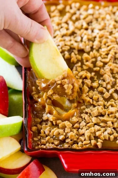 A hand scooping out a serving of caramel apple dip.