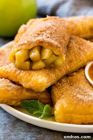 Fried apple pies on a plate served with caramel sauce and topped with cinnamon sugar.